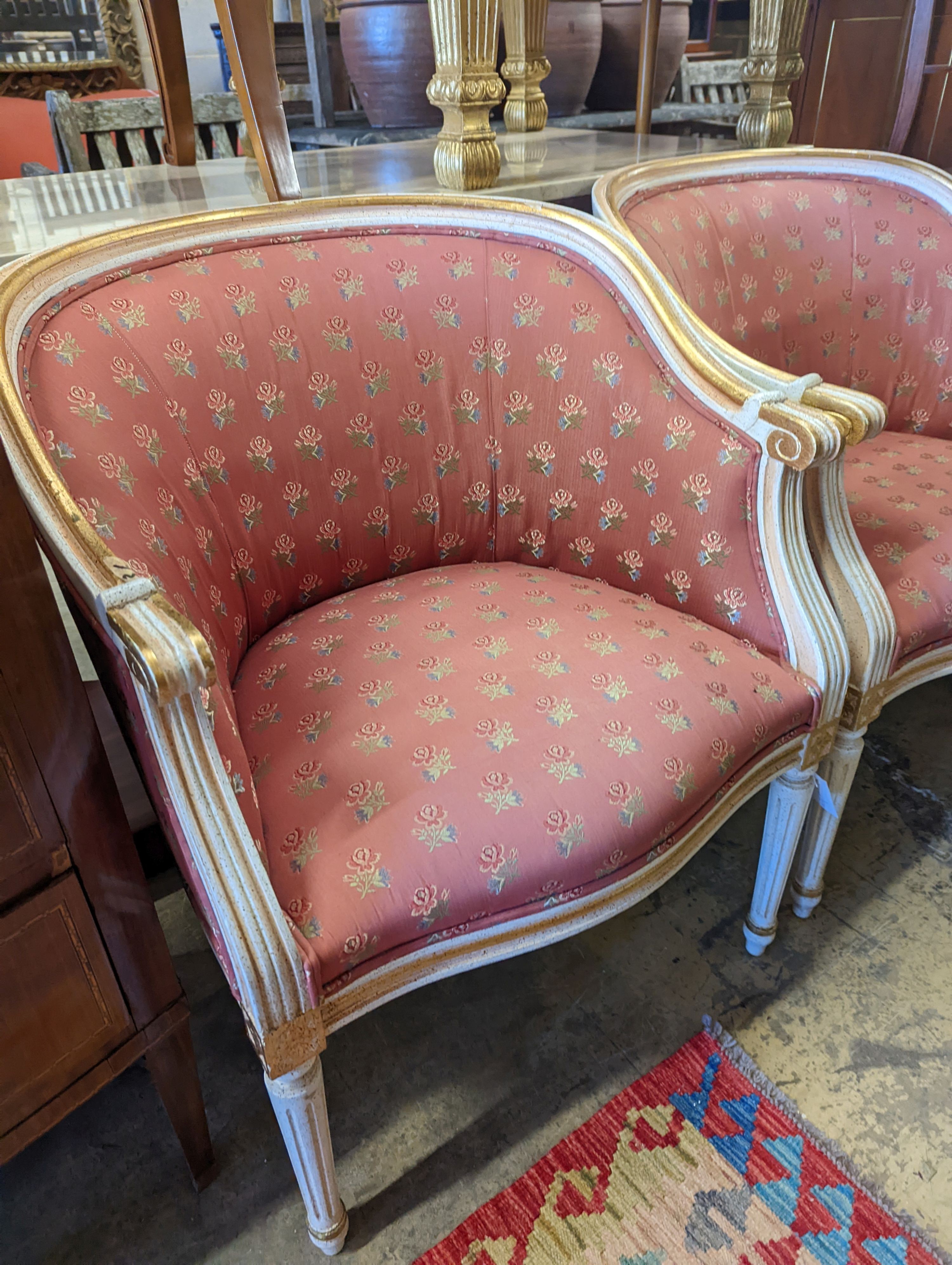 A pair of Louis XVI design painted parcel gilt tub framed chairs, width 65cm, depth 45cm, height 81cm